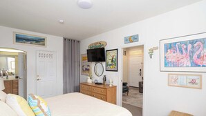 Une chambre à coucher avec un lit, une commode et des œuvres d’art accrochées aux murs.