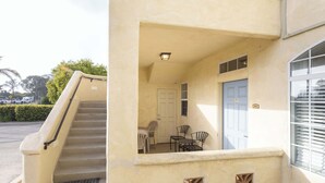 Ein Gebäudeeingang mit Treppe, einer Tür und einer kleinen Terrasse mit Sitzgelegenheiten.