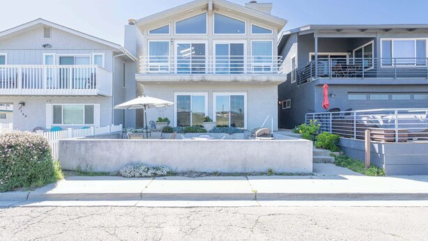 Uma casa moderna com dois andares, varanda, pátio com móveis de exterior e garagem.