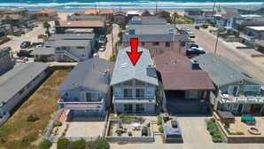 Uma área residencial à beira-mar, com uma casa destacada por uma seta vermelha.
