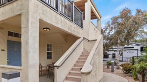 A two-story building with a balcony, a staircase, and a parked RV in the background. - Coastal Cutie (Oceano)