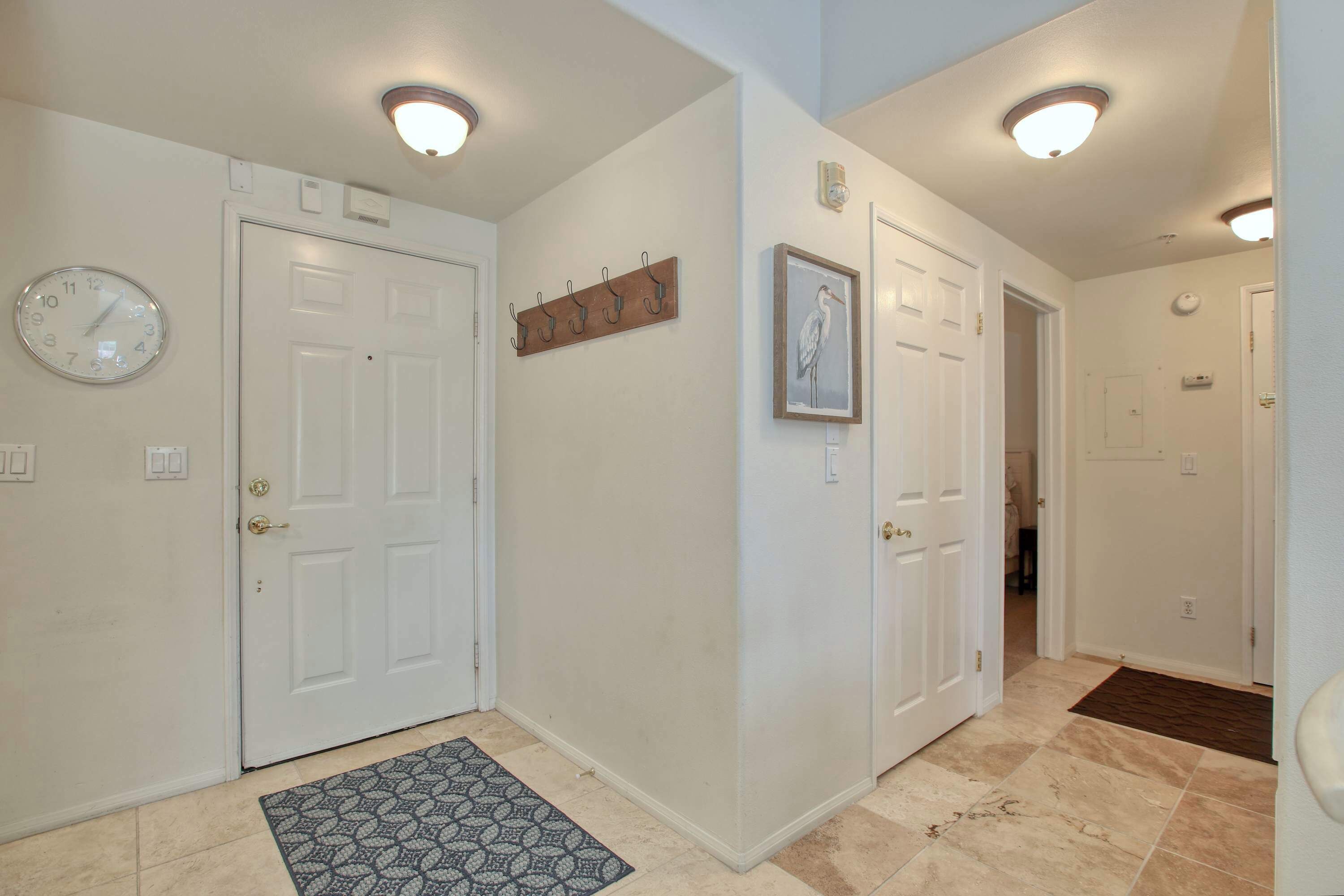 A hallway with white doors, a clock, and a framed picture on the wall.