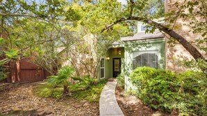A pathway leading to a house with a brick exterior and a green door. - Woodlands Escape: 3BR Texas Retreat w/ Forest View (The Woodlands)