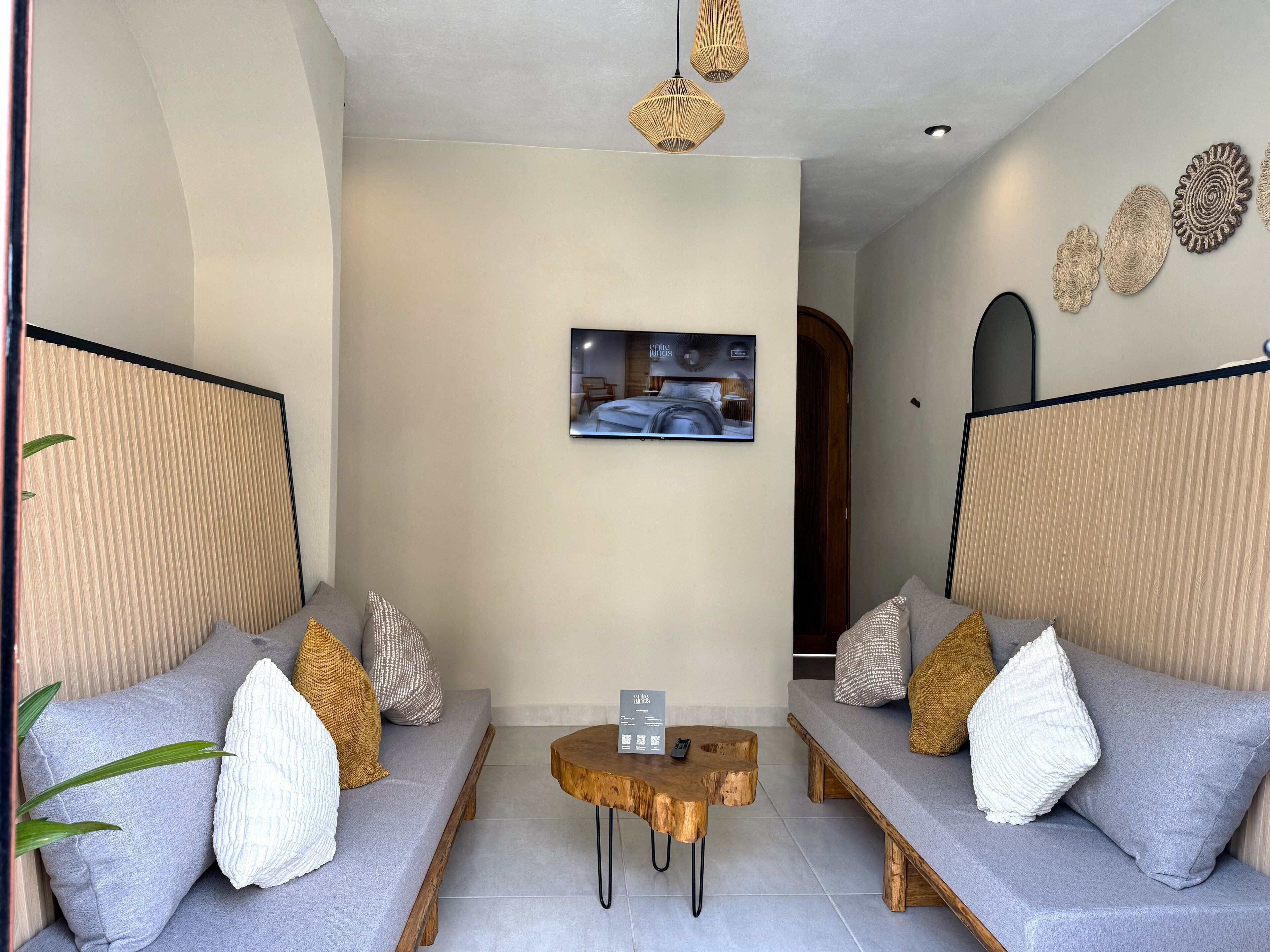 A modern living room with two grey sofas, a wooden coffee table, and a television mounted on the wall.