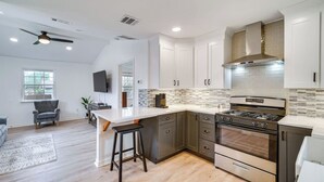 Uma cozinha moderna com uma ilha grande, eletrodomésticos de aço inoxidável e um revestimento de azulejos em padrão herringbone.