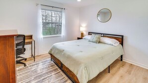 Quarto com cama, escrivaninha, cadeira, janela e ventilador de teto.