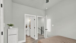 A bedroom with a bed, a dresser, and a door leading to a bathroom. - Pet-Friendly 3BR/3BA • 15 Min to Airport (Humble)