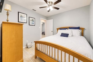 Une chambre à coucher avec un lit en bois, un ventilateur de plafond et une commode.