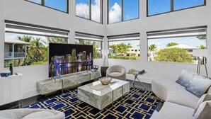 A spacious living room with a large TV, comfortable seating, and a view of the city skyline.