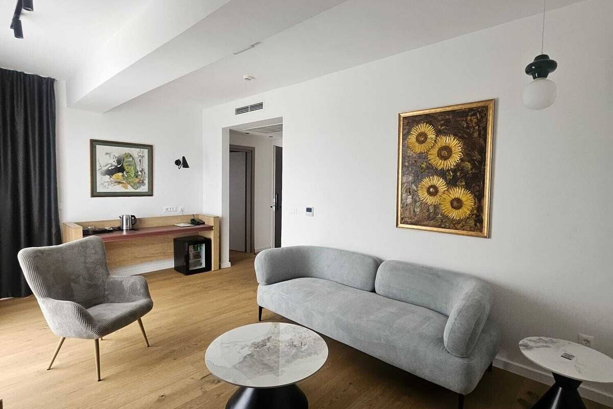 Un salon moderne avec un canapé gris, une table basse ronde, un fauteuil gris et un tableau représentant des tournesols accroché au mur.