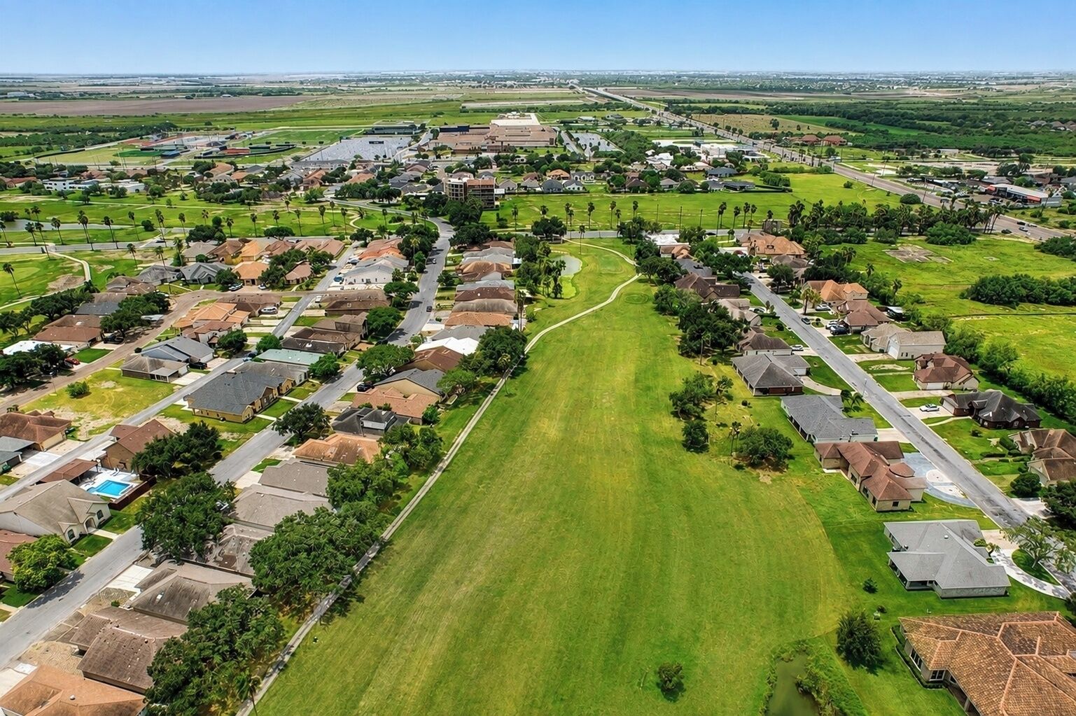 A residential area with houses, roads, and a large green field.