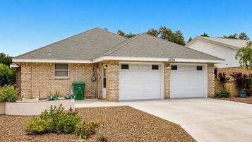 A two-story house with a brick exterior, two garage doors, and a driveway leading to the front entrance.