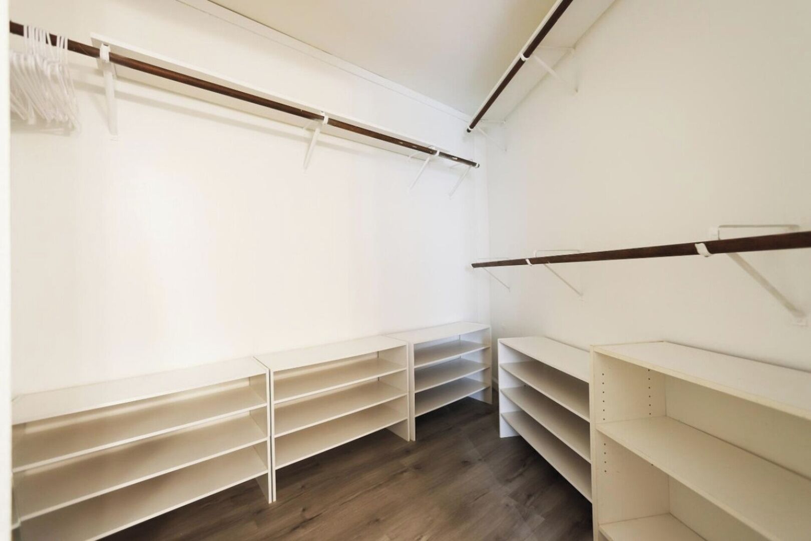 A closet with multiple shelves and hanging rods, organized for storage.