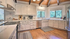 A modern kitchen with white cabinets, a built-in oven, and a stainless steel refrigerator. - Outdoor Deck • Disc/Pool Table • Fireplace • Grill (Camino)