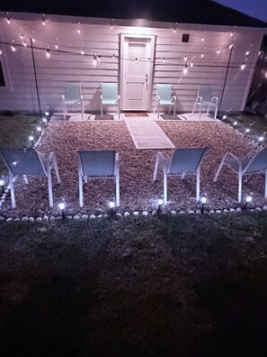 An outdoor seating area with chairs and a table, surrounded by a gravel path and string lights. - New Home in New Community Near Downtown Houston (Houston)
