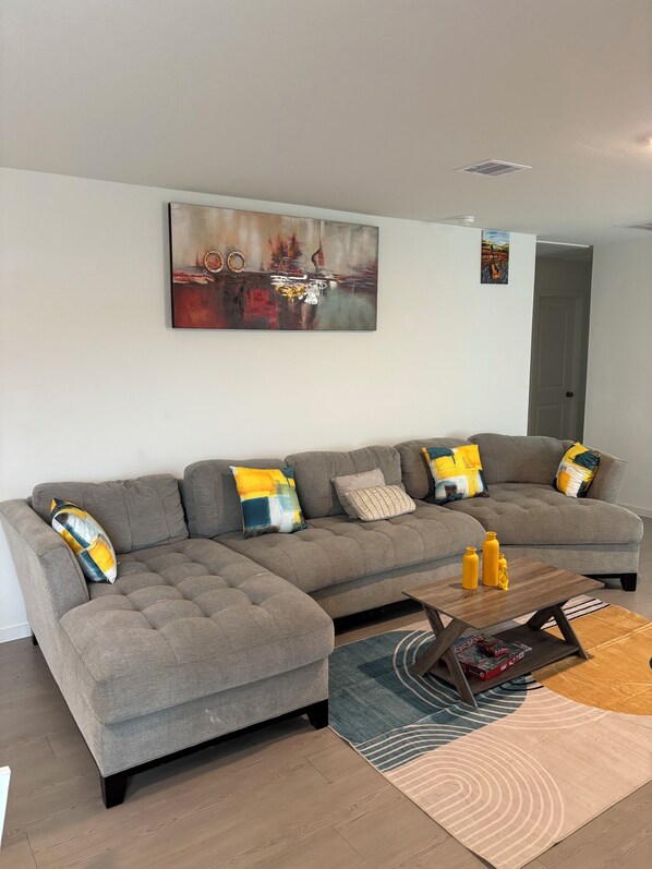 Ein modernes Wohnzimmer mit einer Eckcouch, einem Couchtisch und einem Teppich.