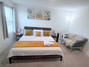 A neatly arranged bedroom with a bed, bedside tables, a lamp, a sofa, and artwork on the wall. - New Home in New Community Near Downtown Houston (Houston)