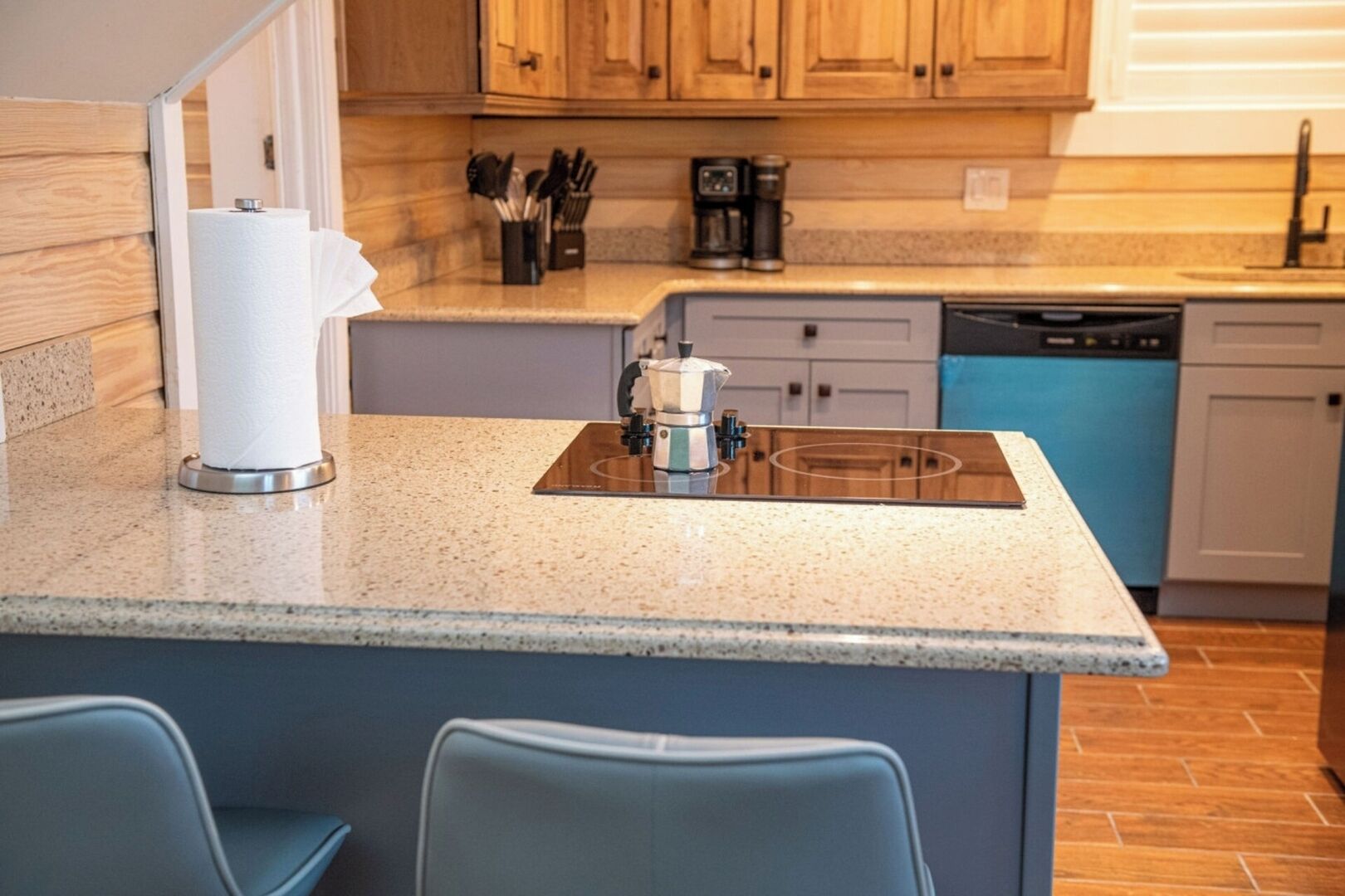 A kitchen with a granite countertop, a coffee maker, and a dishwasher.