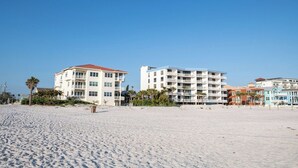 A beachfront hotel with multiple buildings, a sandy beach, and palm trees. - Steps to Beach, Heated Pool, Boutique Queen Studio (Madeira Beach)