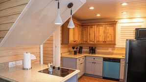A modern kitchen with wooden cabinets, a black refrigerator, and a countertop with a coffee maker and utensils. - Steps to Beach, Heated Pool, Boutique Queen Studio (Madeira Beach)