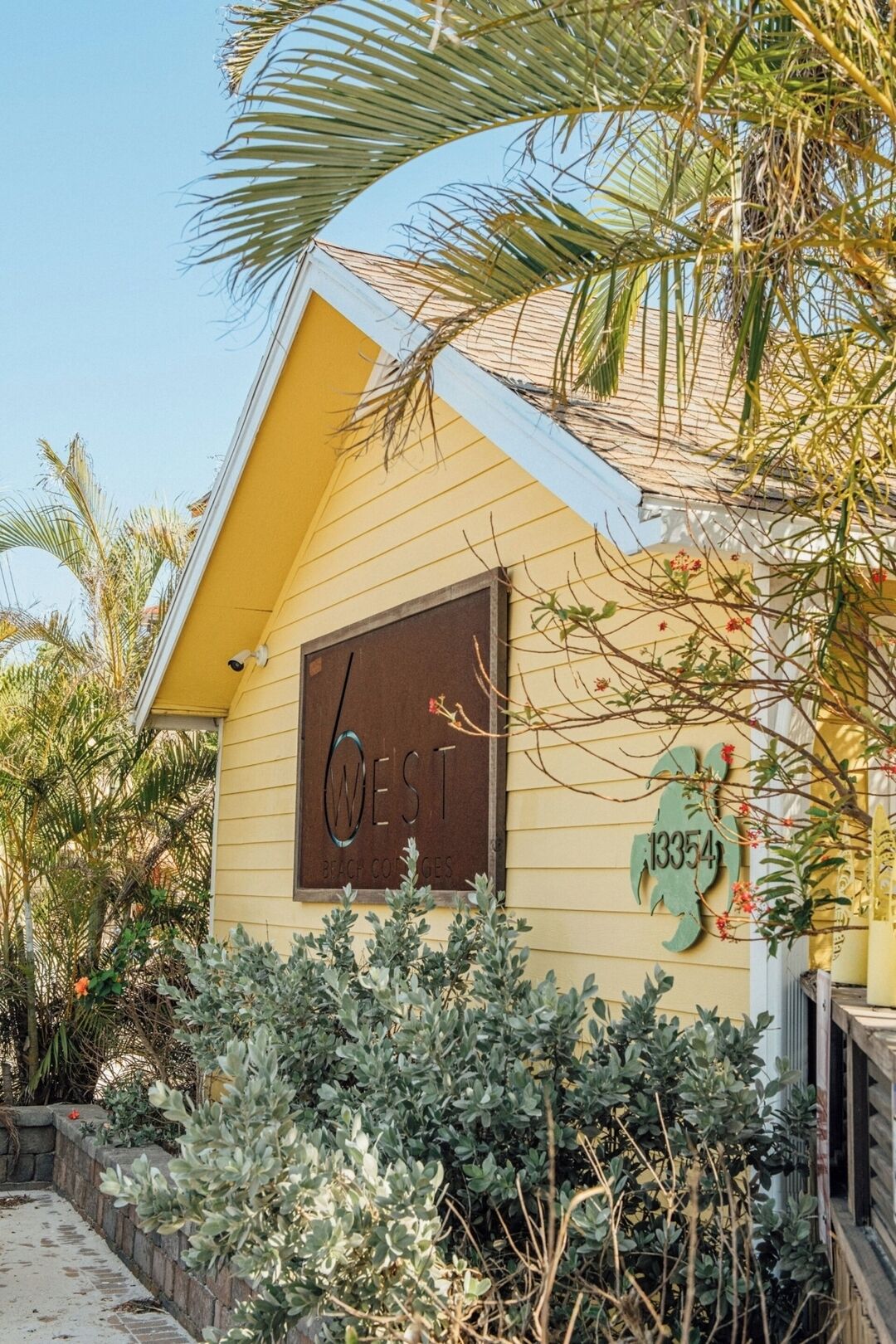A yellow building with a sign reading "West Beach Cottages" and the number "13354".