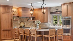 Una cucina con mobili in legno, un'isola centrale con sgabelli da bar ed elettrodomestici integrati.