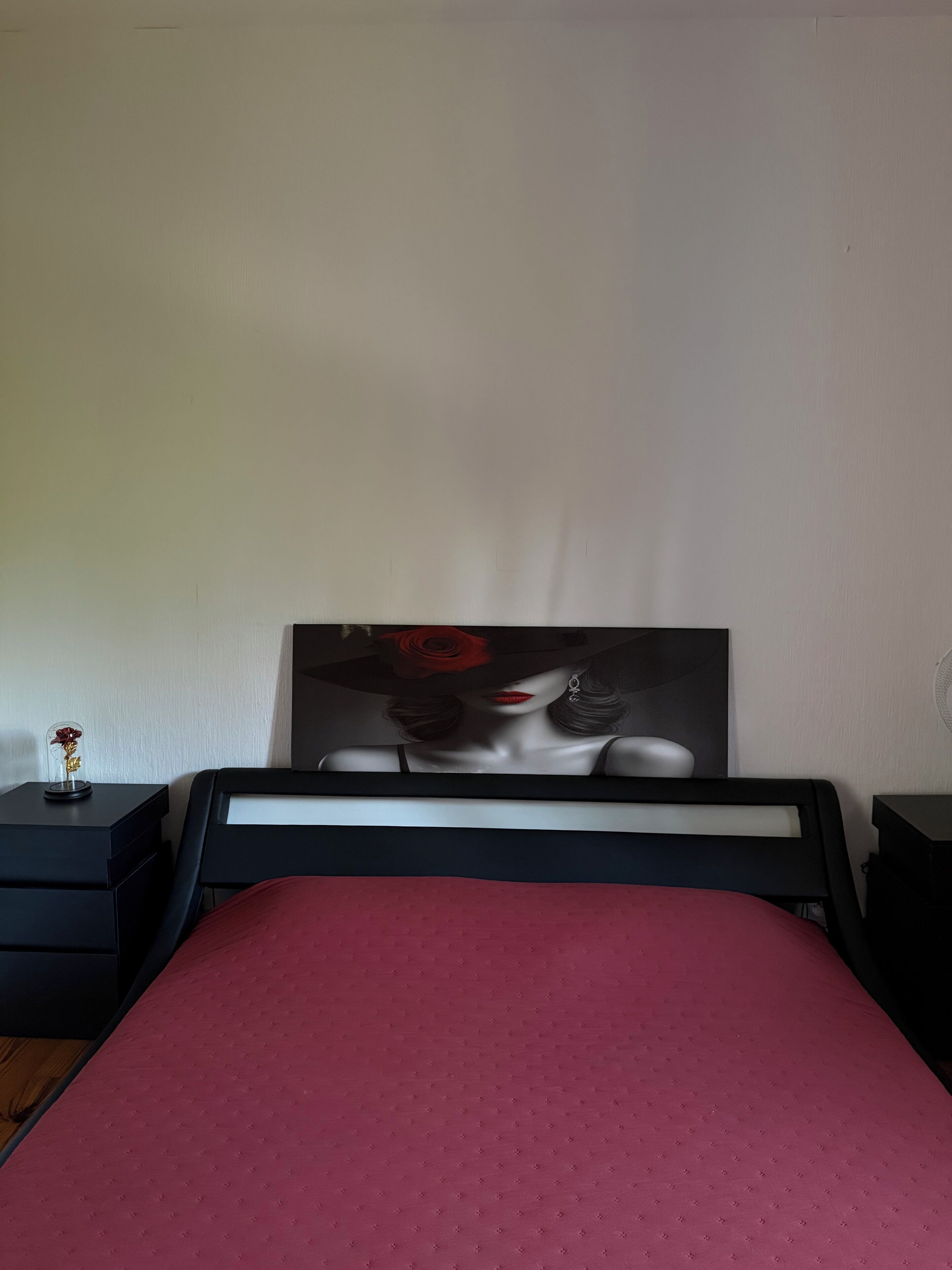 Une chambre à coucher comprenant un lit, une table de chevet, une commode et une œuvre d’art accrochée au mur.