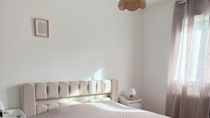 A bedroom with a large bed, a bedside table, a hanging light, and a window with curtains. - Modern house by the sea (Arès)