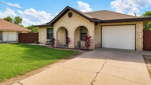 A residential house with a garage, a driveway, and a well-maintained lawn.