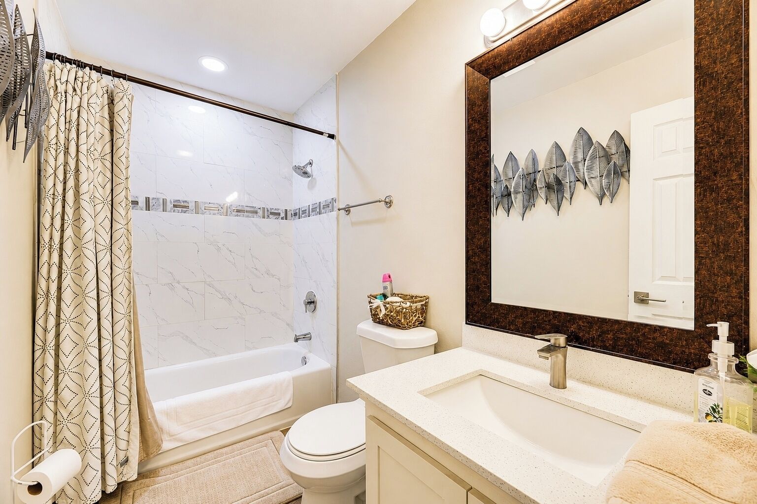 Un baño con ducha, inodoro, lavabo y un espejo grande.
