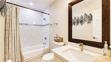 Un baño con ducha, inodoro, lavabo y un espejo grande.
