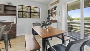 Een eethoek met een houten tafel en stoelen, een raam met uitzicht en een sterdecoratie aan de muur.