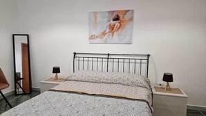 A bedroom with a bed, two bedside tables, a chair, a mirror, and a painting on the wall. - DONNA RUDIAE WILL HOST YOU IN THE HEART OF SALENTO, IN THE CENTER OF DELICIOUS LECCE. (Lecce)