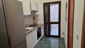 A compact kitchen with a refrigerator, stove, oven, and tiled backsplash. - DONNA RUDIAE WILL HOST YOU IN THE HEART OF SALENTO, IN THE CENTER OF DELICIOUS LECCE. (Lecce)