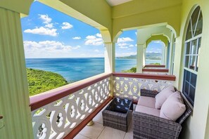 Un balcón con mobiliario de mimbre y vista al océano.