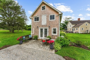A two-story house with a patio, a small table, and chairs. - Historic Ice House Near Mystic (Stonington)