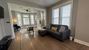 A spacious living room with hardwood flooring, a sectional sofa, and large windows. - Near Lake and Museum • Modern • Game Area (Chicago)