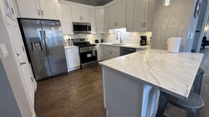 A modern kitchen with white cabinets, stainless steel appliances, and a marble countertop. - Near Lake and Museum • Modern • Game Area (Chicago)