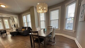 A spacious living room with a dining area, hardwood floors, and large windows with blinds. - Near Lake and Museum • Modern • Game Area (Chicago)
