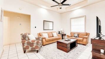 A living room with a ceiling fan, two sofas, a coffee table, and a TV.