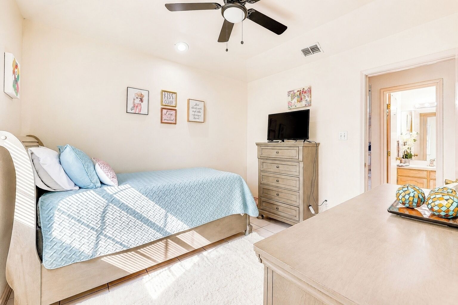 Ein Schlafzimmer mit Bett, Schminktisch, Fernseher und Bildern an der Wand.