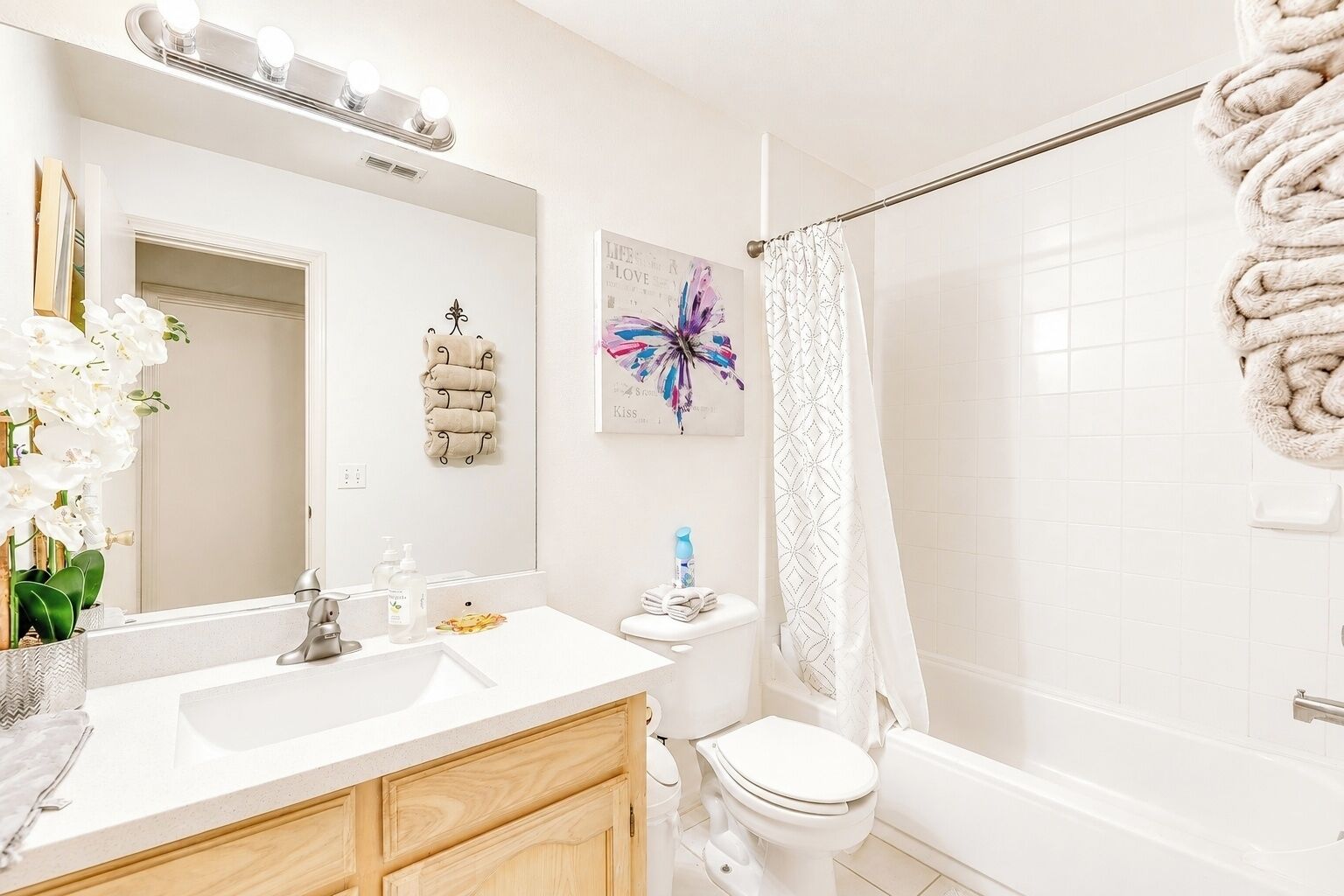 A bathroom with a white sink, mirror, toilet, and shower area.