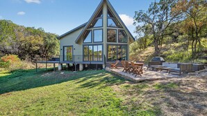 Una casa moderna con una amplia terraza, mobiliario exterior y una zona de barbacoa.