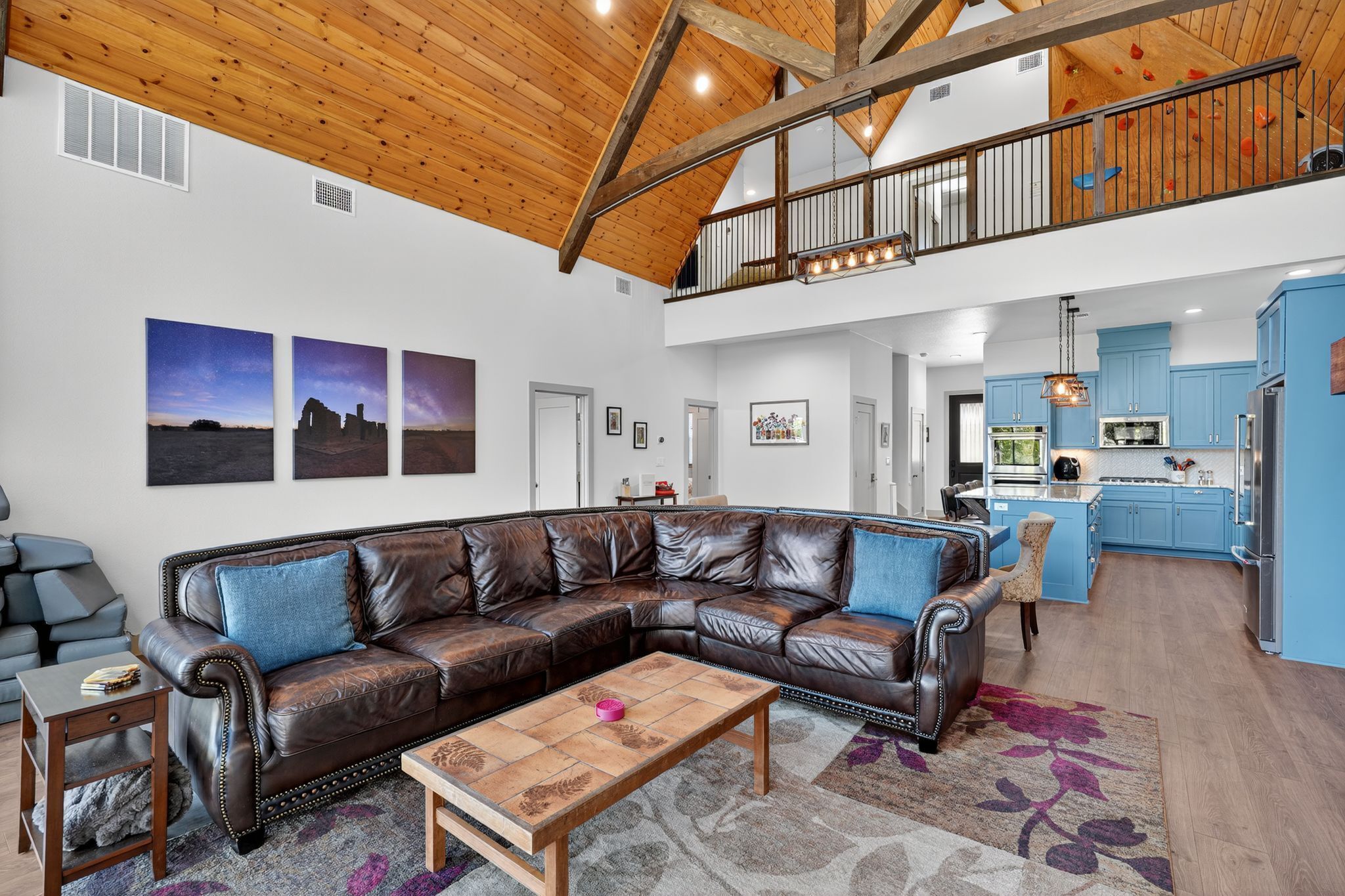 A spacious living room with a leather sectional sofa, a wooden coffee table, and a large rug.