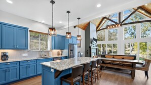 Una cocina moderna con armarios azules, una isla grande con taburetes de bar e iluminación colgante.