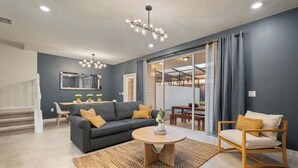 Una sala de estar moderna con un sofá gris, una mesa de centro redonda y una silla de madera.
