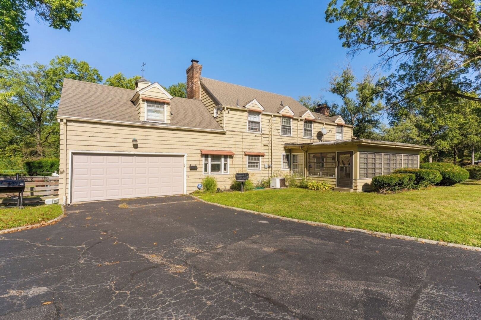 A two-story house with a garage, a covered porch, and a well-maintained lawn.
