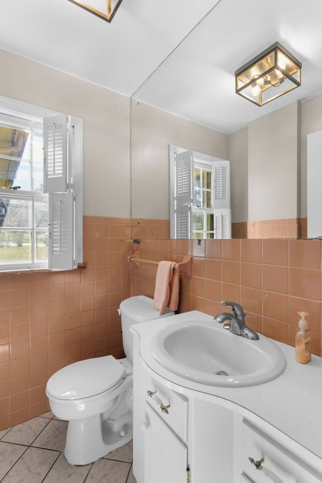 Une salle de bain avec des toilettes, un lavabo et un miroir.