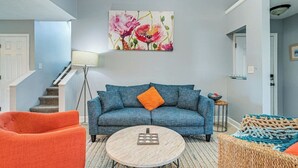 Ein Wohnzimmer mit einem blauen Sofa, einem orangefarbenen Sessel und einem runden Couchtisch.