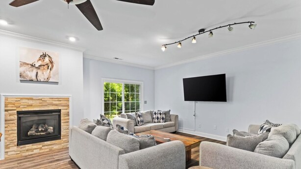 Ein modernes Wohnzimmer mit Kamin, grauen Sofas, einem Couchtisch und einem flachbildfernseher an der Wand.